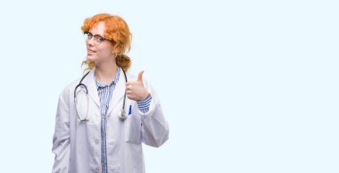 Hareketi el ile mutlu yaşasın yapıyor Doktor üniforma giyen genç Kızıl saçlı kadın. Kameraya bakarak başarı gösteren ile ifade onaylama.