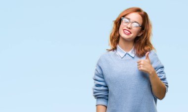 Genç güzel kadın hareketi el ile mutlu yaşasın yapıyor kış kazak giyen izole arka plan yüzünden. Kameraya bakarak başarı gösteren ile ifade onaylama.