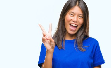 Genç Asyalı kadın mutlu yüz zafer işareti yaparken kameraya göz kırpıyor ile gülümseyen izole arka plan üzerinde. İki numaralı.