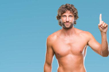 Yakışıklı İspanyol modeli adam seksi ve gömleksiz gösterilen ve kendinden emin ve mutlu gülümseyen bir parmak ile işaret eden oktan yukarı izole arka plan üzerinde.