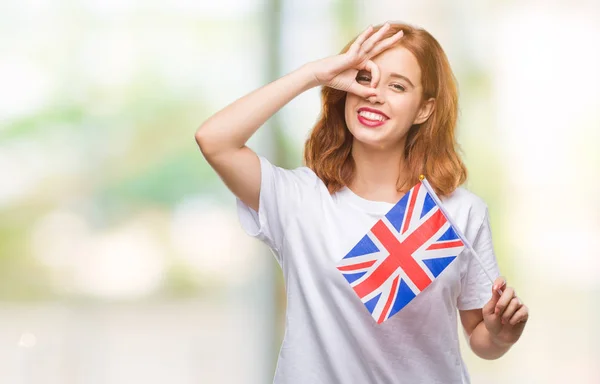 年轻美丽的妇女持有英国国旗在孤立的背景和快乐的脸微笑做 标志用手在眼睛看通过手指 — 图库照片
