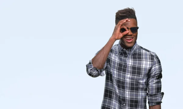 年轻的非洲裔美国人戴墨镜在孤立的背景下做 手势用手微笑 眼睛看通过手指与愉快的面孔 — 图库照片