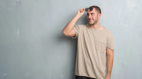 Joven Caucásico Hombre Sobre Gris Grunge Pared Usando Gafas Sol — Foto de Stock