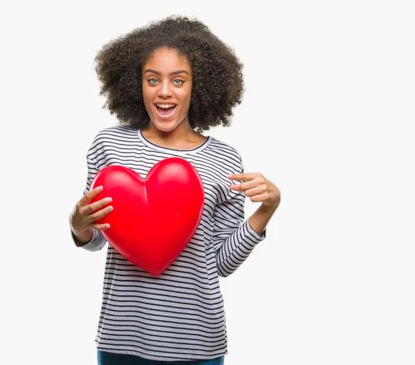 年轻的美国黑人妇女举行红色心脏在爱在隔绝的背景非常愉快指向用手和手指 — 图库照片