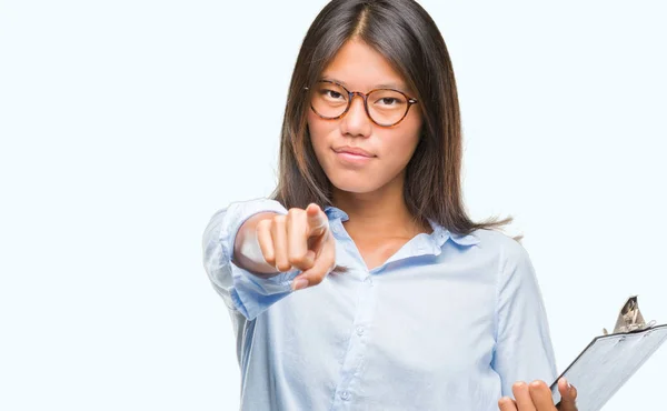 在独立背景下的年轻亚洲商业妇女持有剪贴板指向相机和你 正面和自信的手势从前面 — 图库照片