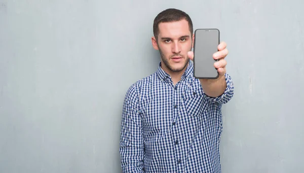 Hombre Caucásico Joven Sobre Pared Grunge Gris Que Muestra Pantalla —  Fotos de Stock