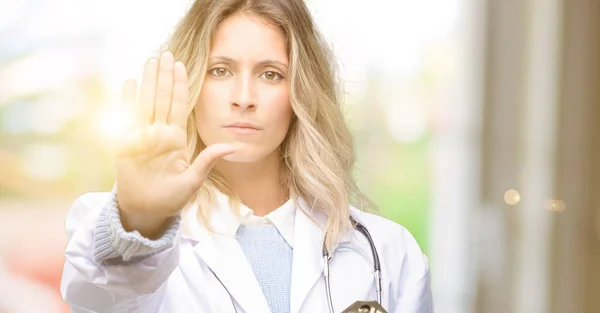 年轻的女医生 医学专业人员对不良的态度感到恼怒 用手做停车标志 表示安全 防卫或限制 也许推挤 — 图库照片