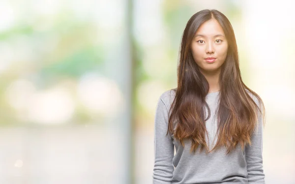 若いアジア女性の顔に真剣な表情で孤立した背景の上 シンプルで自然なカメラを見てください — ストック写真
