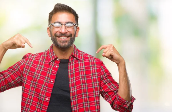 Adult hispanic man wearing glasses over isolated background looking confident with smile on face, pointing oneself with fingers proud and happy.