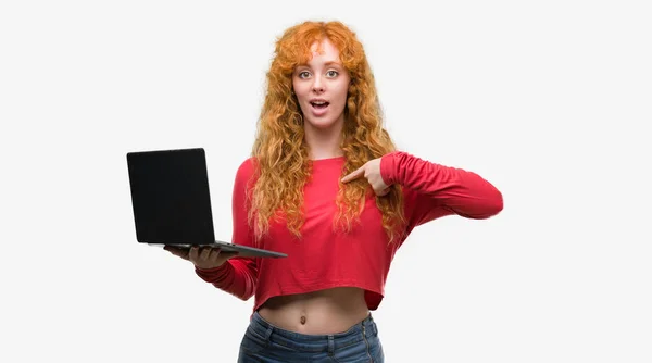 若い赤毛の女性が自分自身に驚き顔ポインティング指でラップトップ コンピューターを使用して — ストック写真