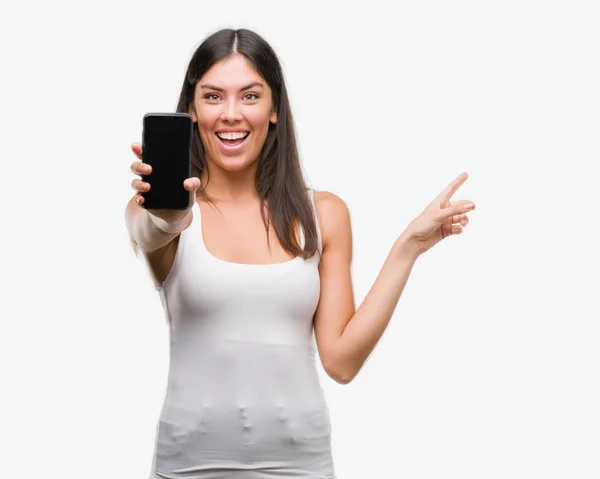 Young Beautiful Hispanic Showing Smartphone Very Happy Pointing Hand Finger — Stock Photo, Image