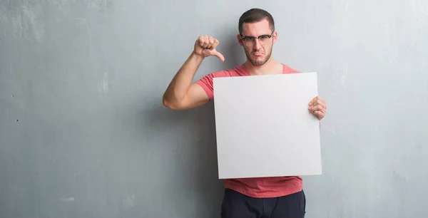 Young Caucasian Man Grey Grunge Wall Holding Blank Banner Angry — Stock Photo, Image