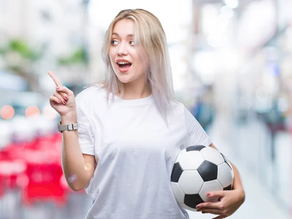 蓝色背景的年轻金发女子举行足球足球球 — 图库照片