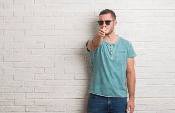 Young Caucasian Man Standing White Brick Wall Wearing Sunglasses Pointing — Stock Photo, Image