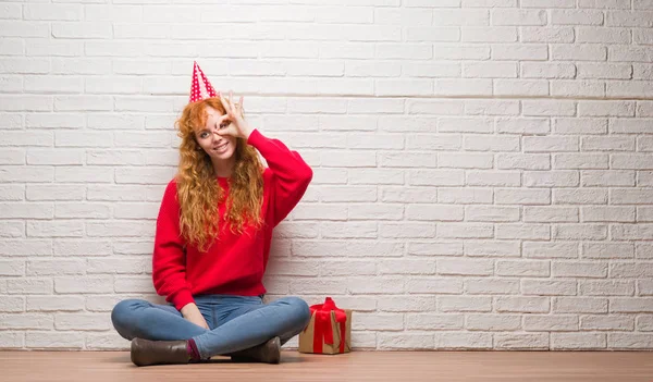 Unga Rödhårig Kvinna Sitter Över Tegelvägg Som Bär Födelsedag Hatt — Stockfoto