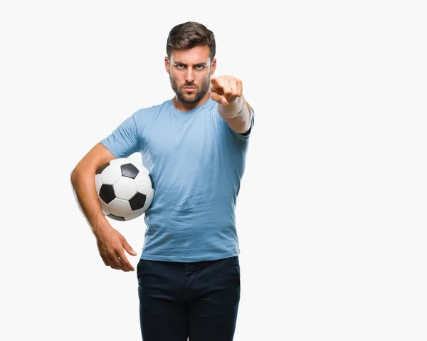 年轻英俊的男子举行足球足球在孤立的背景下指向相机和你 正面和自信的手势从前面 — 图库照片