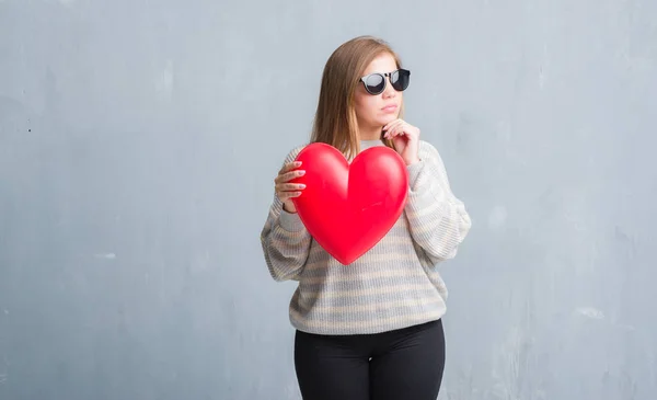 Joven Mujer Adulta Sobre Gris Pared Grunge Sosteniendo Corazón Rojo — Foto de Stock