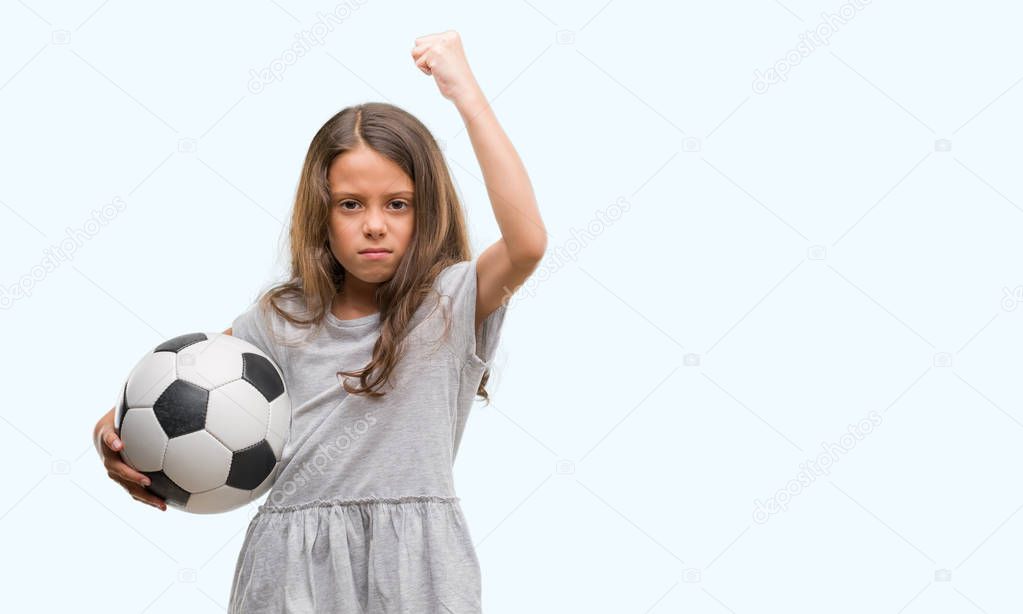 Brunette hispanic girl holding soccer football ball annoyed and frustrated shouting with anger, crazy and yelling with raised hand, anger concept