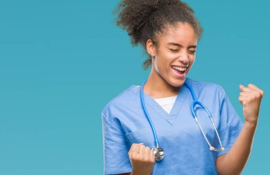 Gülümseyen ve başarı için çığlık genç afro Amerikalı doktor kadın yüzünden izole arka plan çok mutlu ve heyecanlı kaldırdı, silah ile kazanan jest yapıyor. Kutlama kavramı.