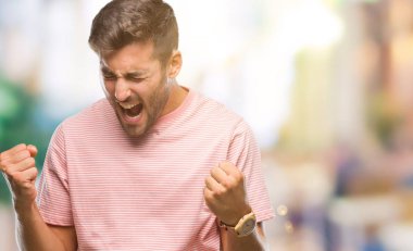 Soyutlanmış, mutlu ve heyecanlı genç bir adam kollarını kaldırmış, gülümseyen ve başarı için çığlık atan kazanan bir jest yapıyor. Kutlama konsepti.