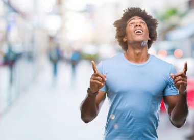 Afro Amerikalı adam izole arka plan üzerinden hayran ve yukarıya bakıp parmakları ile işaret şaşırttı ve silah kaldırdı.