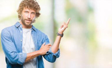 Kameraya bakarak yan el ve parmak ile işaret eden yakışıklı İspanyol modeli adam yüzünde kocaman bir gülümseme ile izole arka plan üzerinde.