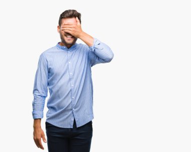 Yakışıklı genç gülümseyen ve gözler için sürpriz kapsayan yüz el ile gülüyor izole arka plan üzerinde. Kör kavramı.