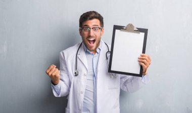 Yakışıklı genç doktor adam gurur çığlık ve zafer ve başarı çok heyecanlı, kutluyor gri grunge duvar holding Pano duygu tezahürat