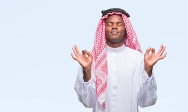 Geleneksel keffiyeh izole arka plan üzerinde giyen genç Arapça Afrika adam rahatla ve gülümseyen gözlerle kapalı parmak jestle meditasyon yapıyor. Yoga kavramı.