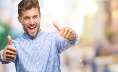 Yakışıklı delikanlı el ile pozitif jest yapıyor onaylama izole arka plan üzerinde başparmak gülümseyen ve başarı için mutlu. Kamera, kazanan jest arıyorsunuz.