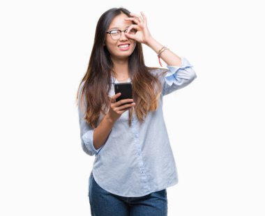 Mutlu yüz el parmaklarının arasından seyir göz üzerinde ok işaretiyle yapıyor gülümseyen izole arka plan üzerinde Smartphone kullanarak Genç Asyalı kadın manifatura