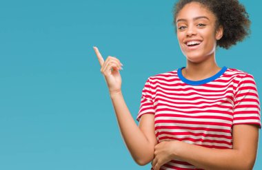 Yüzünde kocaman bir gülümseme ile izole arka plan üzerinde genç afro Amerikalı kadın kameraya bakarak yan el ve parmak ile işaret.