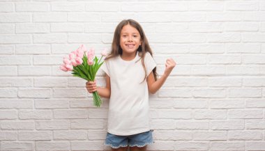 Duygu tezahürat genç İspanyol çocuğun gurur çığlık ve zafer ve başarı çok heyecanlı, kutluyor anneler günü çiçek tutan beyaz tuğla duvarın üzerinden