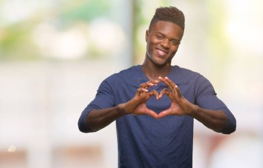 Afrikalı-Amerikalı genç aşık kalp simgesi ve elleriyle şekil gösteren gülümseyen izole arka plan üzerinde. Romantik kavramı.