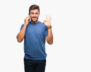 Smartphone üzerinde parmak, mükemmel sembolü ile ok işareti yapıyor izole arka plan üzerinde konuşan genç yakışıklı adam