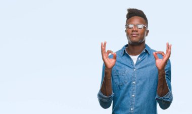 Genç Afro-Amerikan adam izole arka plan üzerinde dinlenmek ve gülümseyen gözlerle parmak ile meditasyon jest yapıyor kapalı. Yoga kavramı.