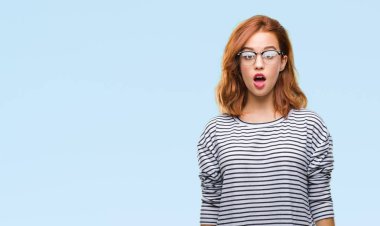 İzole arka plan korkuyor ve şok sürpriz ifade, korku ve heyecan yüz ile gözlüklü genç güzel kadın.