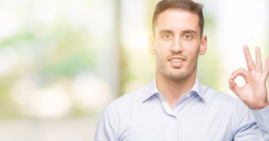 El ve parmak ile ok işareti yapıyor olumlu gülümseyen yakışıklı genç iş adamı. Başarılı ifade.