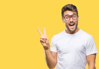 Mutlu yüz zafer işareti yaparken kameraya göz kırpıyor ile gülümseyen izole arka plan üzerinde gözlük takan yakışıklı delikanlı. İki numaralı.