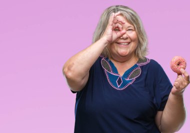 Kıdemli artı el parmaklarının arasından seyir göz üzerinde ok işaretiyle yapıyor gülümseyen mutlu yüz ile arka plan beyaz kadın üzerinde şeker donut yemek izole boyutu