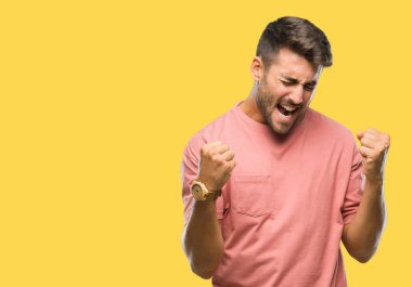 Soyutlanmış, mutlu ve heyecanlı genç bir adam kollarını kaldırmış, gülümseyen ve başarı için çığlık atan kazanan bir jest yapıyor. Kutlama konsepti.