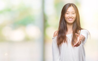 Genç Asyalı kadın dostu sunan el sıkışma tebrik ve davet edici olarak gülümseyen izole arka plan üzerinde. Başarılı iş.