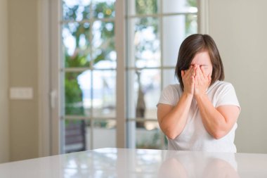 Yüzünü elleriyle ağlayarak süre kapsayan üzgün ifade ile Down sendromu kadın evde. Depresyon kavramı.