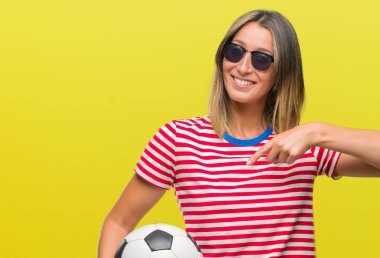 Sürpriz yüz işaret parmağı kendini izole arka plan üzerinde futbol futbol topu tutan genç güzel kadın