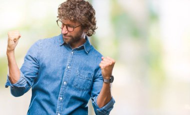 Üzerinde gözlük takan yakışıklı İspanyol model adam arka plan çok mutlu ve heyecanlı kaldırdı, silah ile kazanan jest yapıyor gülümseyen ve başarı için çığlık izole. Kutlama kavramı.