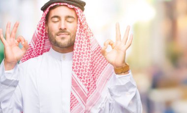 Genç yakışıklı adam giyen keffiyeh izole arka plan üzerinde dinlenmek ve gülümseyen gözlerle parmak ile meditasyon jest yapıyor kapalı. Yoga kavramı.