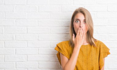 Güzel genç kadın beyaz tuğla duvar kapağı ağız elle hata, korku, ifade için utanç ile şok yüzünden sessizlik içinde gizli kavramı korkuttu