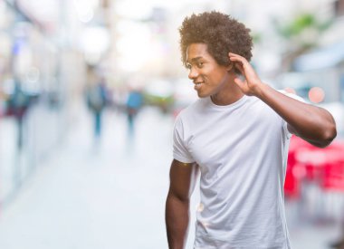 Bir işitme söylenti ya da dedikodu için dinleme kulak üzerinde el ile gülümseyen izole arka plan üzerinde Afro Amerikalı adam. Sağırlık kavramı.