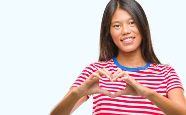 Genç Asyalı kadın kalp simgesi ve elleriyle şekil gösterilen aşık gülümseyen izole arka plan üzerinde. Romantik kavramı.