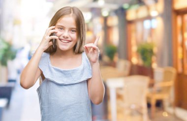 Genç güzel kız telefonda konuşurken arka plan bir fikir ya da soru işaret parmağı gülen yüz, bir numara ile sürpriz izole